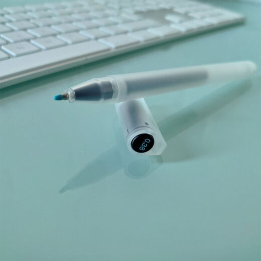 Noto Pepa Productfotografie MUJI Gel-Inktpen 0,38 mm in zwart, zicht vanaf de punt met dop, op bureau met computertoetsenbord