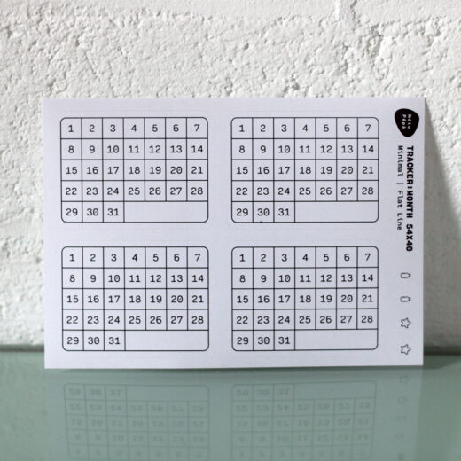 Productfotografie Maandelijkse gewoonte-tracker Stickervel op bureau met witte bakstenen muur als achtergrond