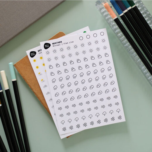 Product Fotografie Weersomstandigheden stickervel - Schattig & Minimalistische stijl op creatief bureau met schetsboek, planner en potloden