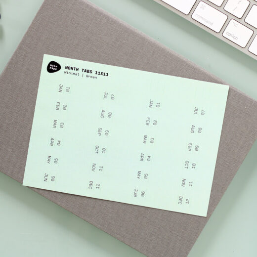 Noto Pepa Minty Green Afgekorte Maand Tabs Stickervel voor twee jaar op een bullet journal notitieboekje op bureau met toetsenbord