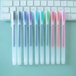 Noto Pepa Productfotografie MUJI Gel Inktpen met Dop Type - Set van 10 (0,38mm) Kleuren op bureau en toetsenbord, zicht vanaf de zijkant van de pennen