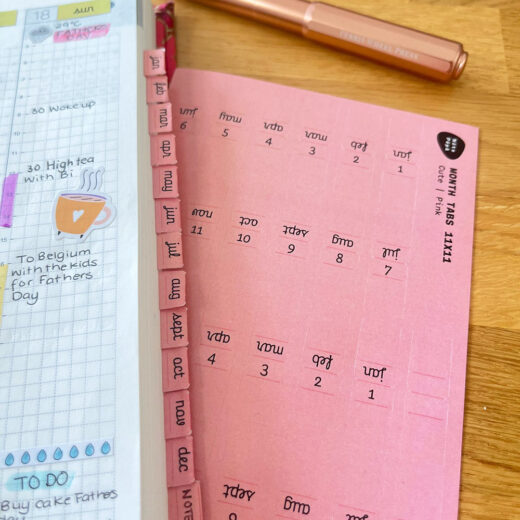 Echt gebruik Noto Pepa Peachy Pink Afgekorte Maand Stickersheet Cute stijl op Hobonichi planner, scène op houten bureau met koperen pen
