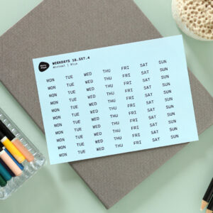 Noto Pepa Baby Blauw afgekorte Weekdagen Stickervel op werk bureau met notitieblok en kleurpotloden